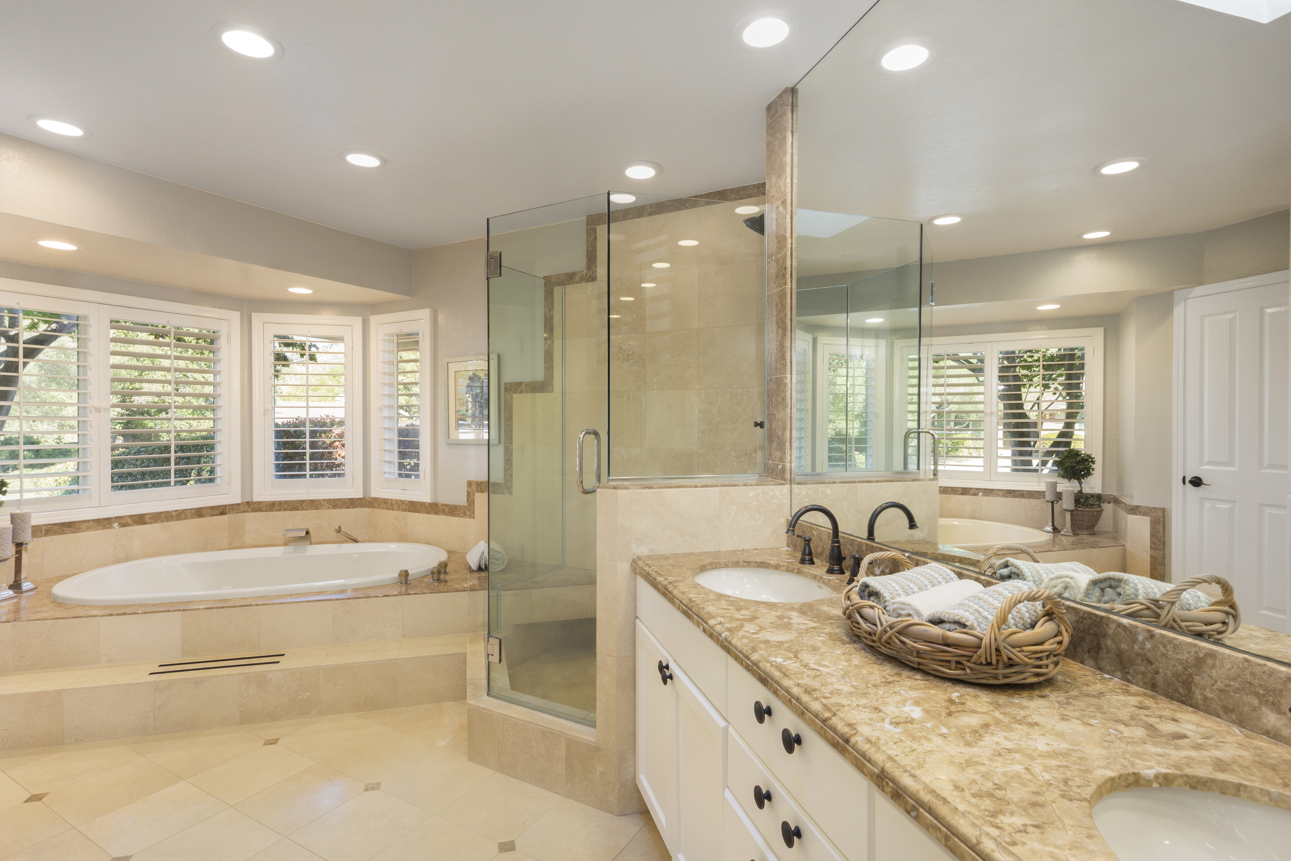 Luxury bathroom interior in marble with glass shower and oval bath tub and round shaped double sink.