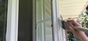 Someone painting exterior door of a house white